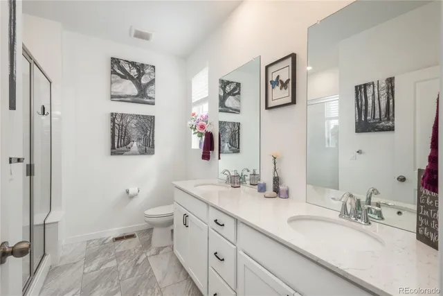 a bathroom with a granite countertop double vanity sink mirror and toilet