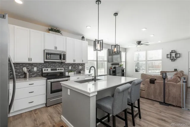 a kitchen with stainless steel appliances granite countertop a kitchen island hardwood floor sink stove and white cabinets