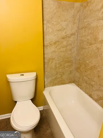 a white toilet sitting next to a white tub