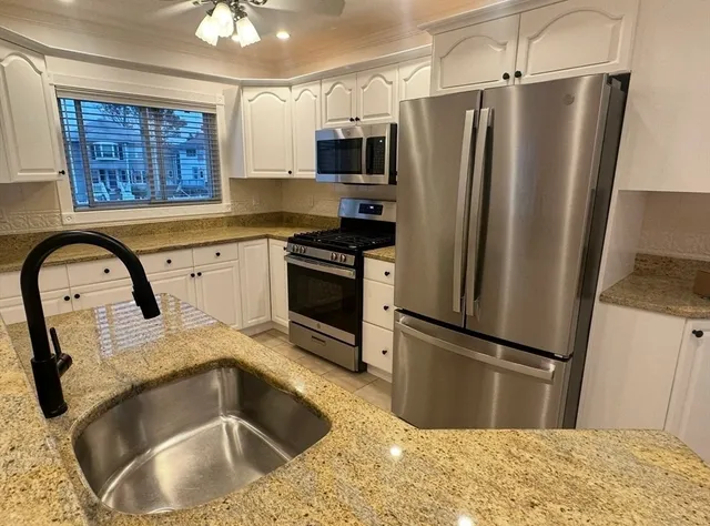 a kitchen with stainless steel appliances granite countertop a refrigerator a stove and a sink with wooden floor