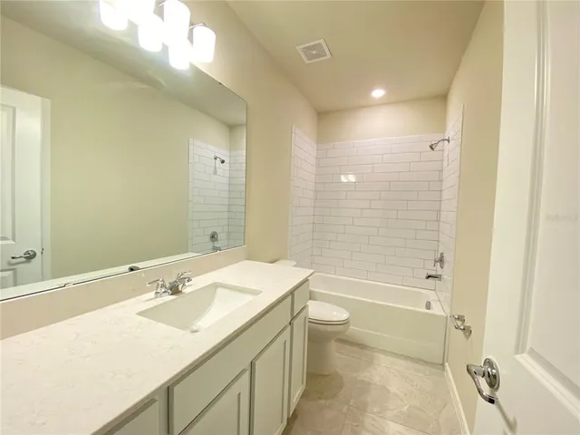 a bathroom with a granite countertop sink a toilet and shower