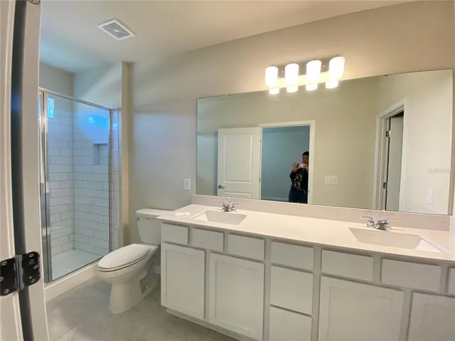 a bathroom with a double vanity sink mirror and toilet