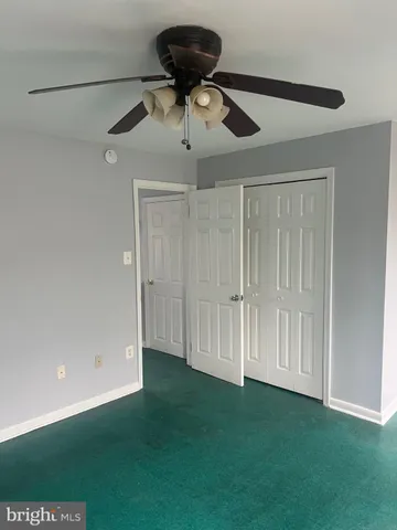 a view of a room with a ceiling fan and hardwood floor