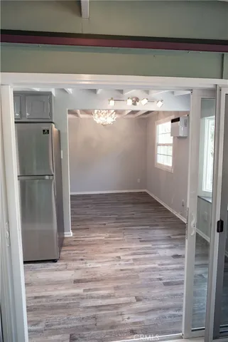 a view of empty room with wooden floor and kitchen view