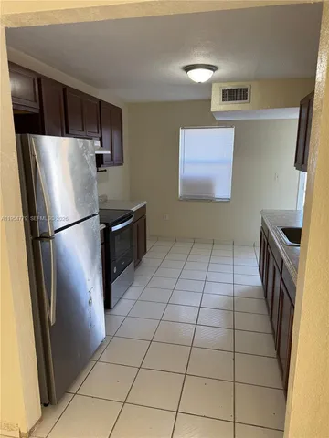 a kitchen with granite countertop a refrigerator and a stove top oven