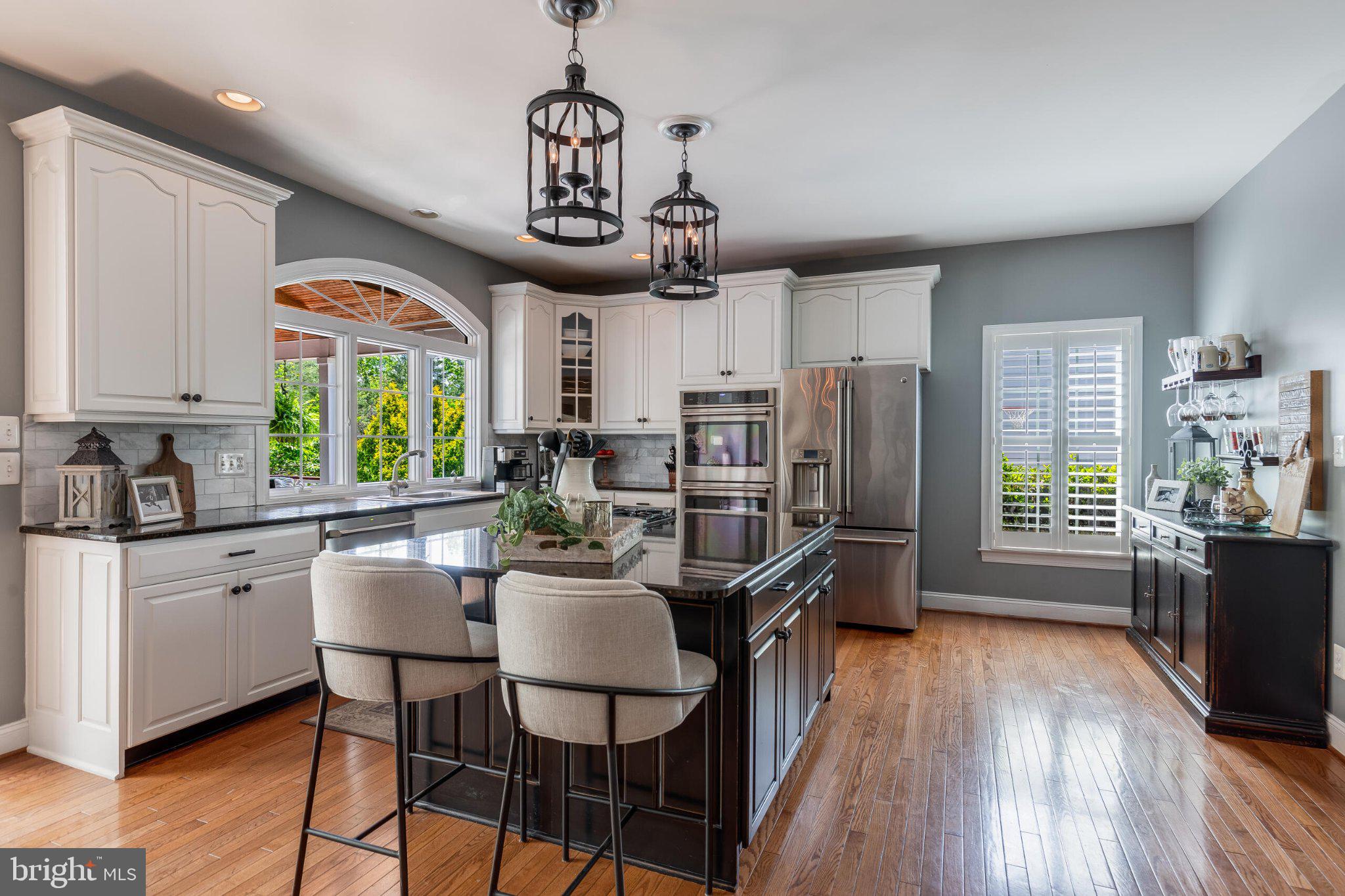 25554 Mimosa Tree Court Chantilly, VA 20152 - Photo 26 of 85 a kitchen with stainless steel appliances granite countertop a stove top oven a refrigerator a sink dishwasher a dining table and chairs with wooden floor