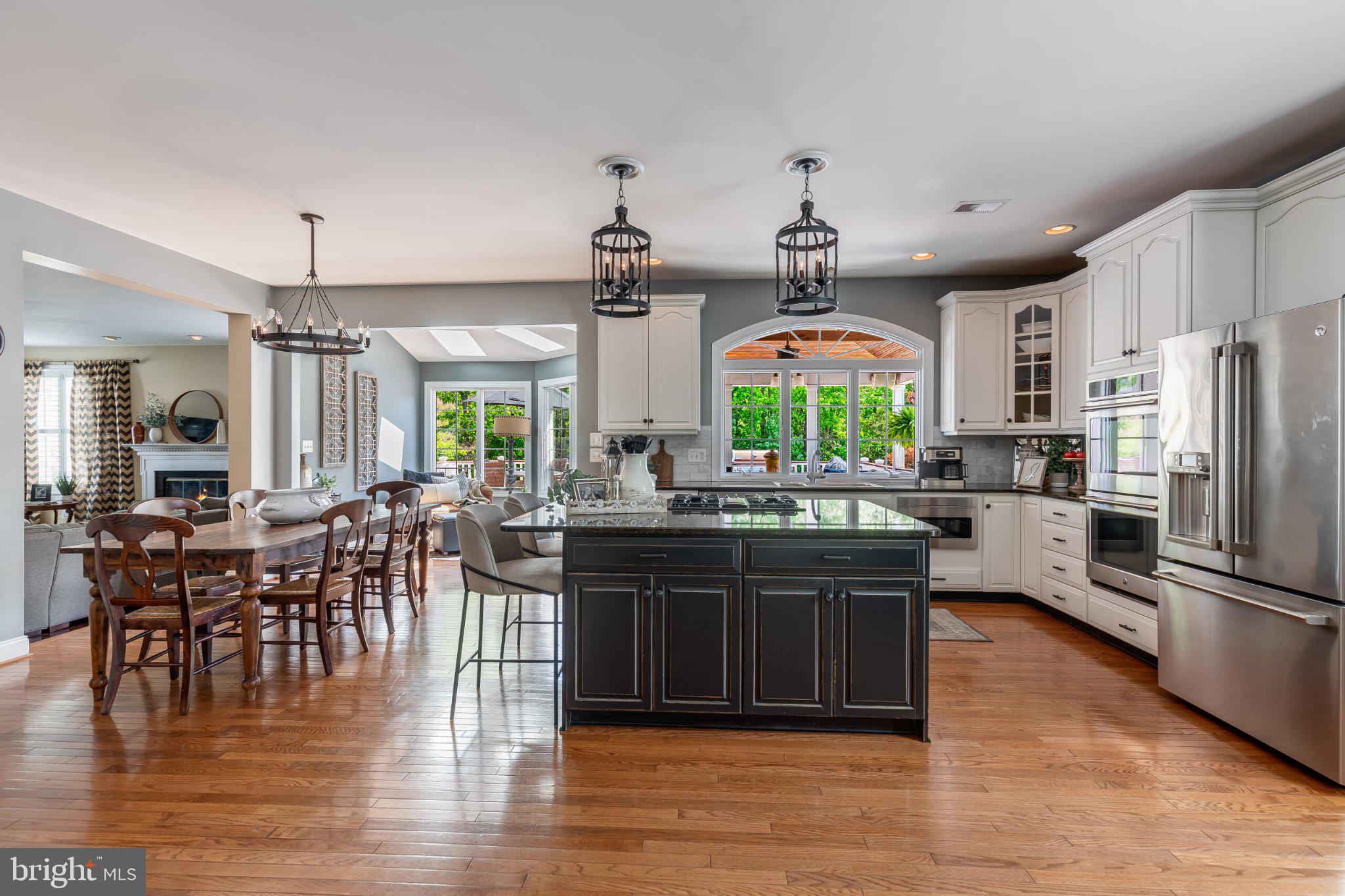 25554 Mimosa Tree Court Chantilly, VA 20152 - Photo 27 of 85 a kitchen with stainless steel appliances granite countertop a stove top oven a refrigerator a dining table and chairs with wooden floor