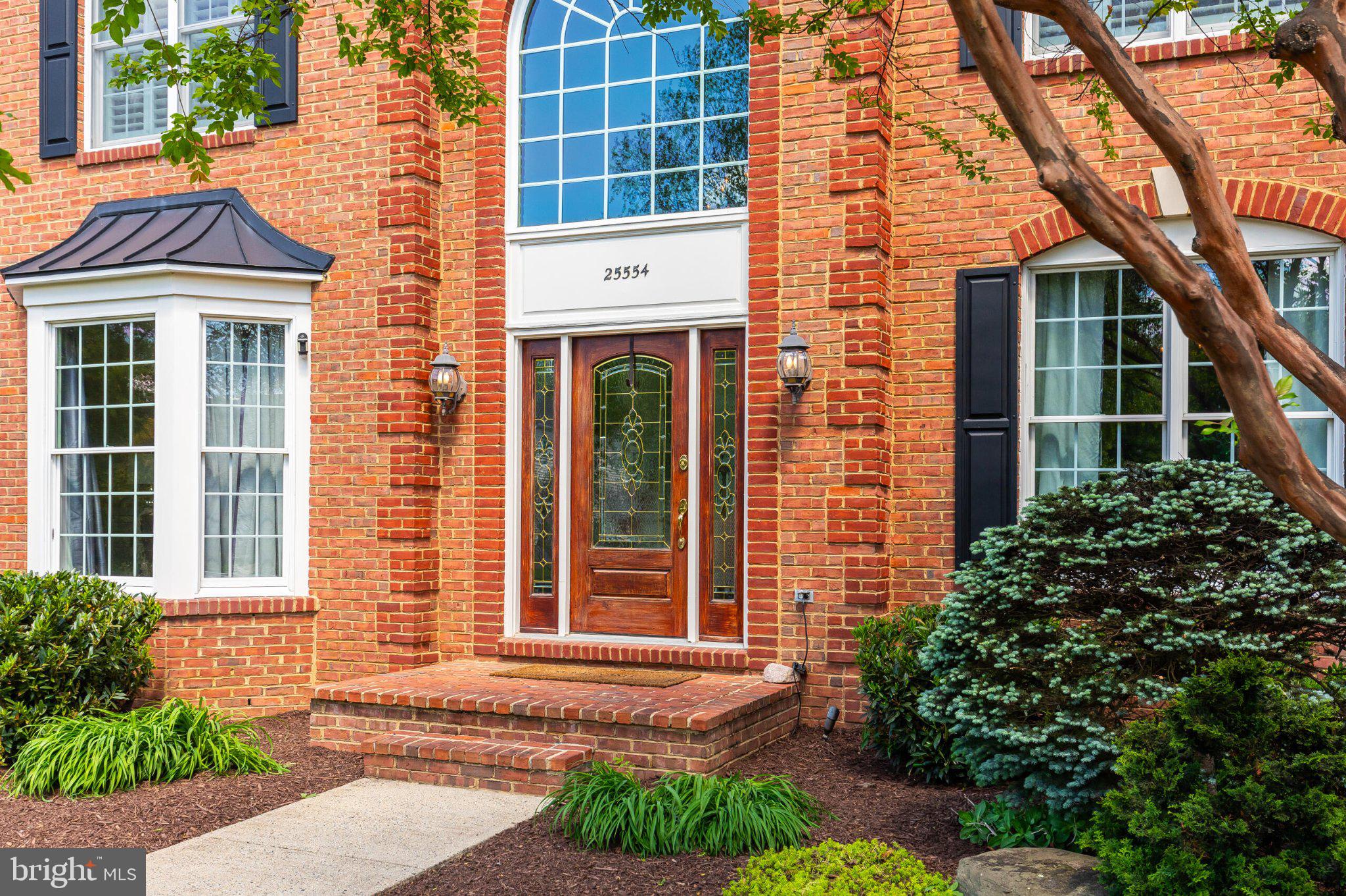 25554 Mimosa Tree Court Chantilly, VA 20152 - Photo 7 of 85 a view of a brick house with large windows and a yard