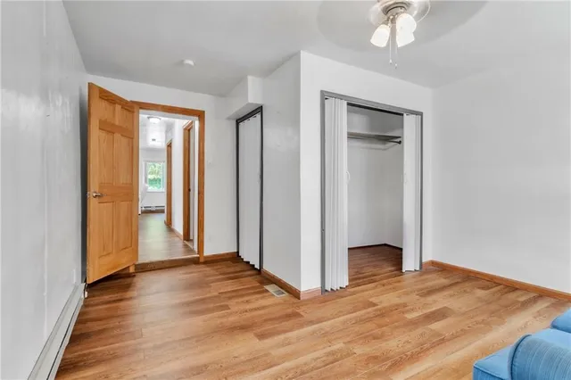 a view of empty room with wooden floor and fan