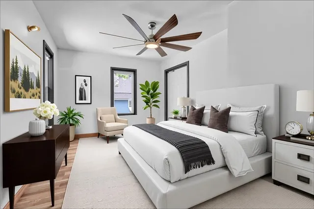 a spacious bedroom with a bed a chandelier and a potted plant