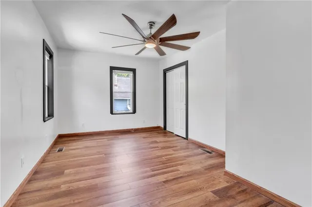 an empty room with wooden floor closet and windows