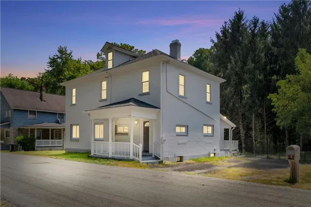 a view of a big house with a big yard and large trees