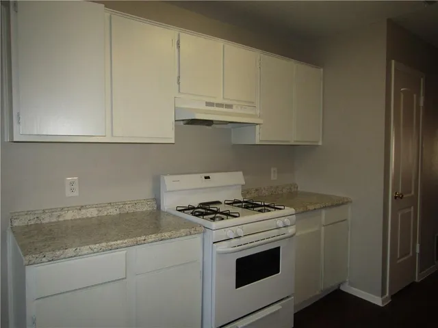 a kitchen with granite countertop white cabinets and white stove