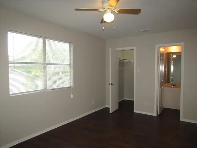 an empty room with wooden floor closet and windows