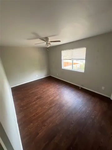 an empty room with a ceiling fan and windows