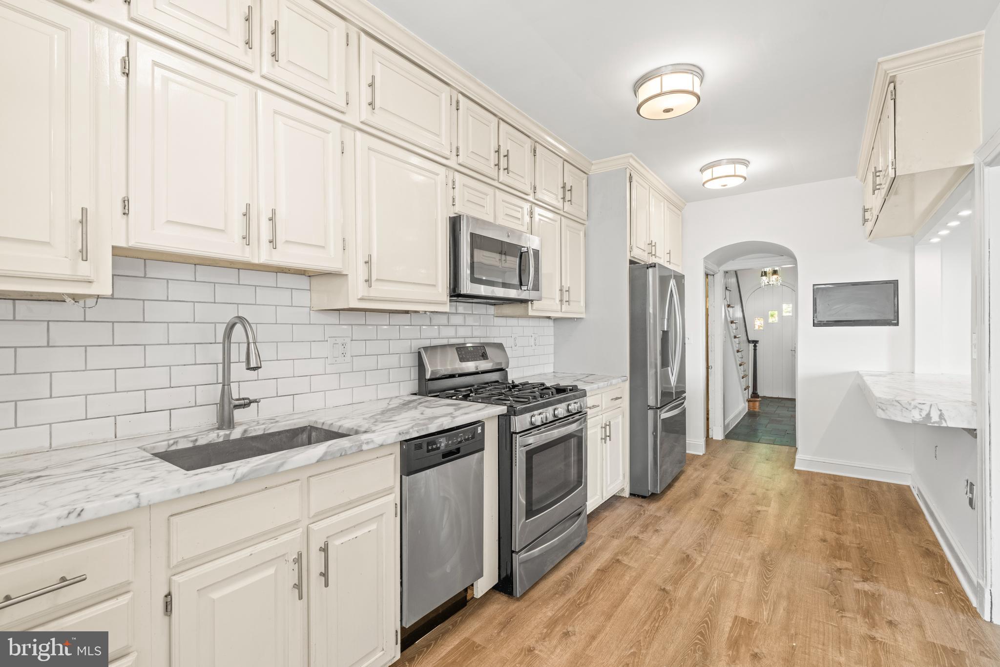 309 Hopkins Road Baltimore, MD 21212 - Photo 11 of 36 a kitchen with stainless steel appliances granite countertop a sink and cabinets with wooden floor