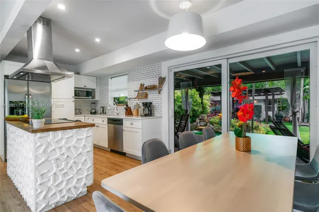 a living room with furniture a potted plant and kitchen view