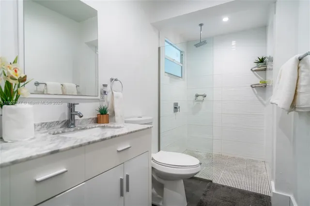 a bathroom with a granite countertop sink a toilet and shower
