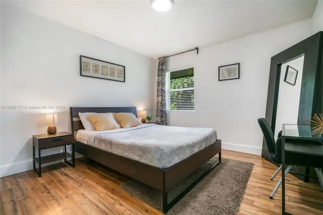 a bedroom with a bed table chair and a window
