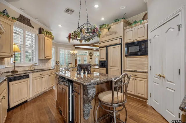 a kitchen with stainless steel appliances granite countertop a table chairs stove and refrigerator
