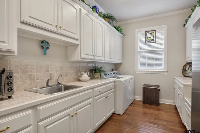 a kitchen with a sink dishwasher and white cabinets with wooden floor