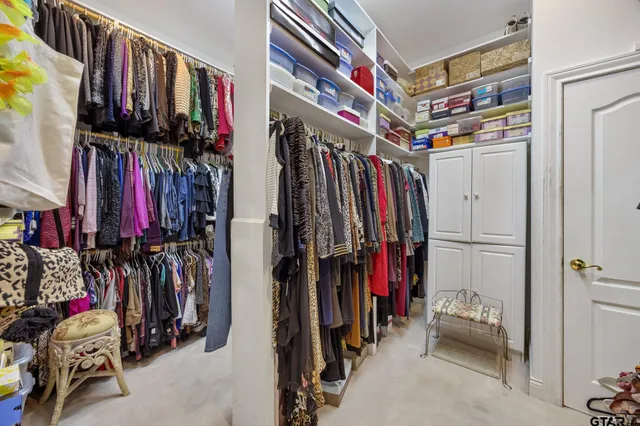 a view of walk in closet with clothes and shoes