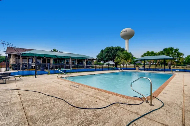 a view of a swimming pool with a bench and some potted plants