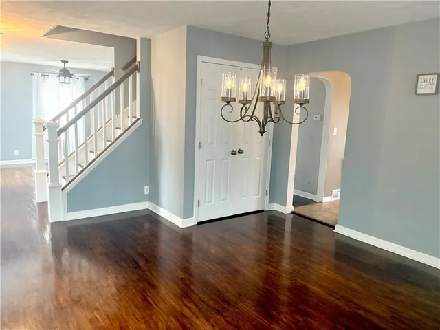 a view of hallway with wooden floor and chandelier