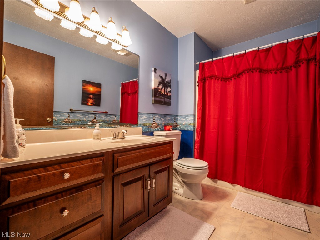 9452 Pleasant Hill Road Northwest Dundee, OH 44624 - Photo 20 of 35 Bathroom featuring mirror, a textured ceiling, large vanity, and light tile floors