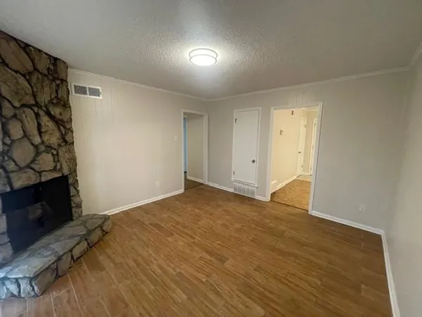 a view of an empty room with wooden floor and a fireplace