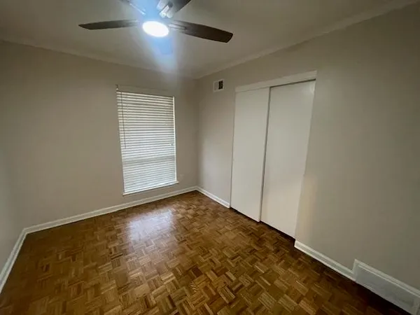 an empty room with wooden floor cabinet and windows