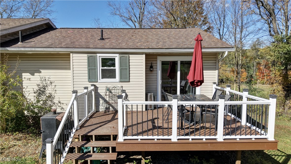 4244 Murray Road Dover, OH 44622 - Photo 21 of 29 Back of property featuring roof with shingles, outdoor dining space, and a wooden deck