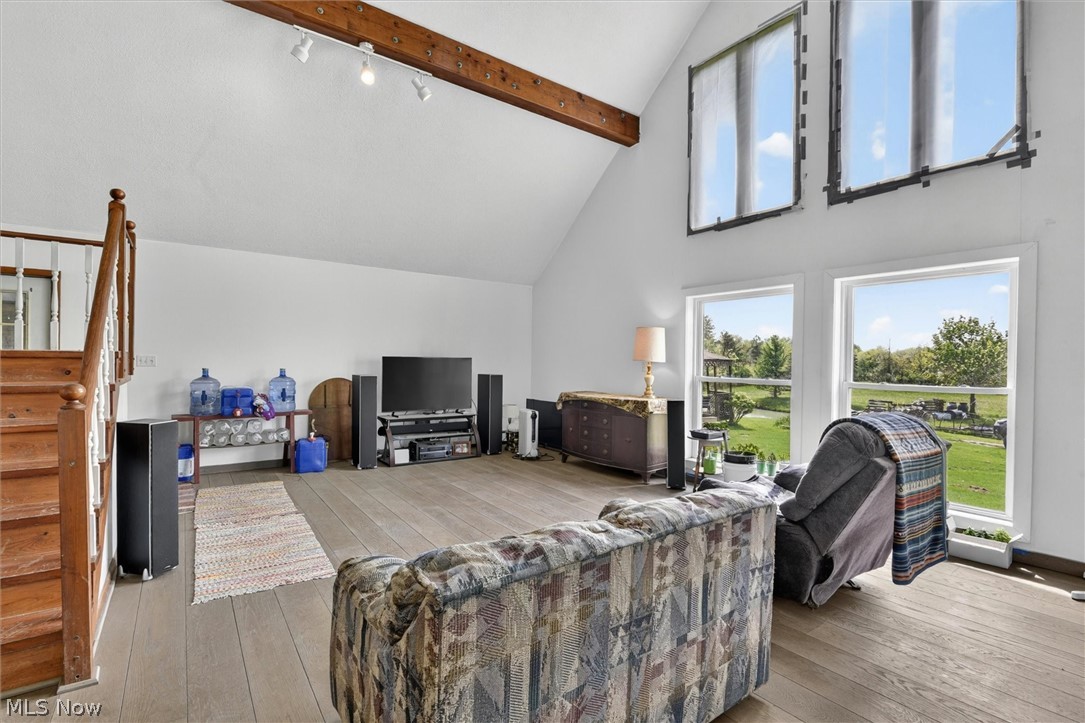 1526 Stevenson Road Ashtabula, OH 44004 - Photo 12 of 50 Spacious living area featuring vaulted ceilings with exposed wood beams, wood-finish flooring, and large windows providing abundant natural light