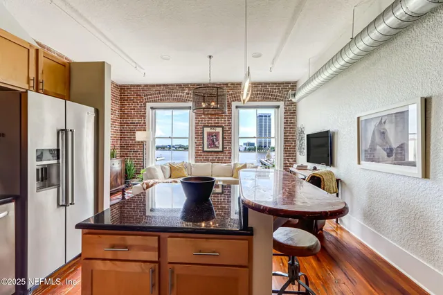 a kitchen with stainless steel appliances granite countertop a refrigerator a stove and white cabinets with wooden floor