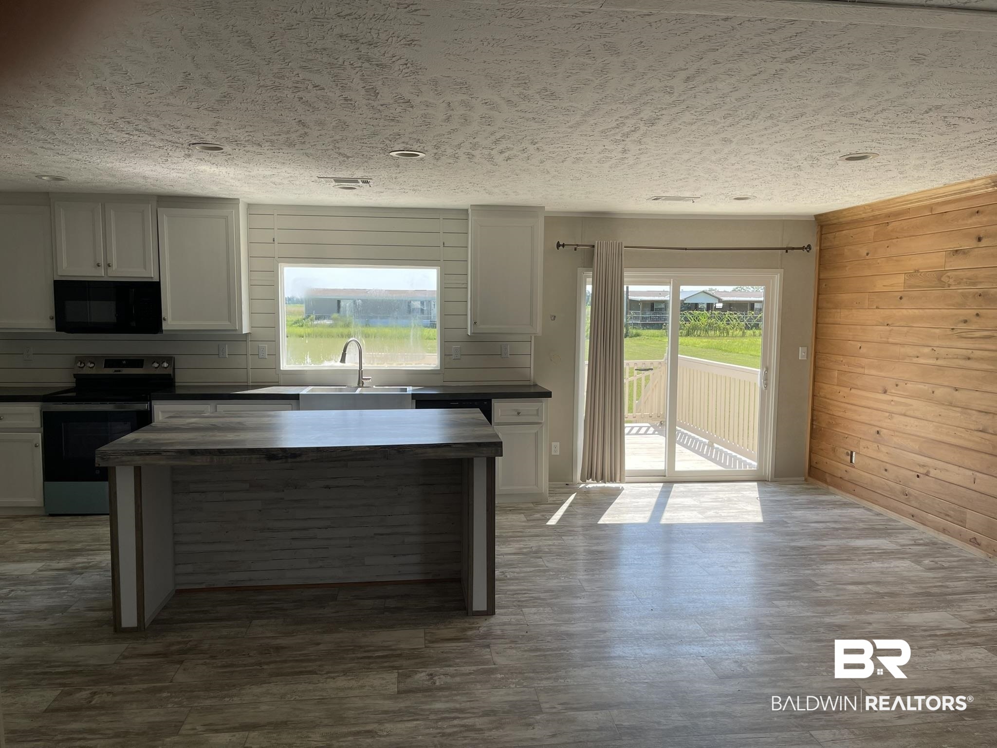 16802 County Road 87 Elberta, AL 36530 - Photo 5 of 19 Kitchen featuring dark countertops, stainless steel range with electric stovetop, wooden walls, white cabinetry, and dark wood-type flooring