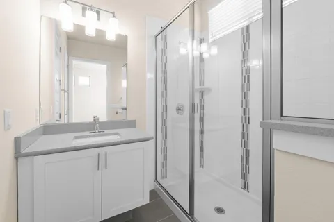 a bathroom with a granite countertop sink two mirror and a shower