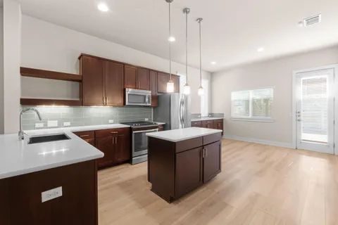 a kitchen with stainless steel appliances granite countertop a sink a stove and a wooden floors