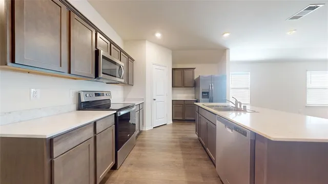 a large kitchen with stainless steel appliances granite countertop a sink and dishwasher a stove top oven with wooden floor