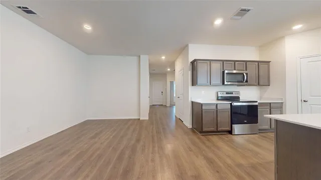 a view of a kitchen with a sink and a stove top oven with wooden floor