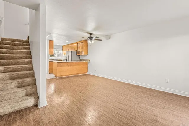 a view of a room with wooden floor and a ceiling fan