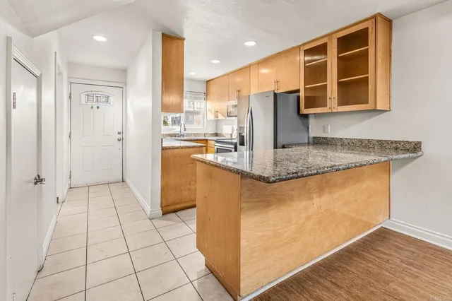 a kitchen with stainless steel appliances granite countertop a refrigerator a oven and white cabinets with wooden floor