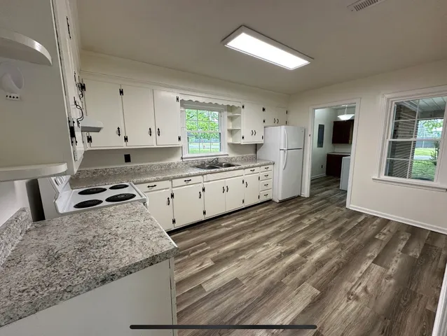 a kitchen with granite countertop a sink a stove and cabinets