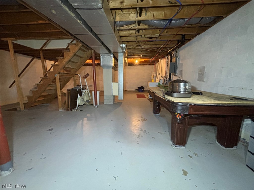 57575 Marietta Road Byesville, OH 43723 - Photo 21 of 25 Unfinished basement featuring exposed wood joists, concrete block walls, painted concrete flooring, and an open wood staircase