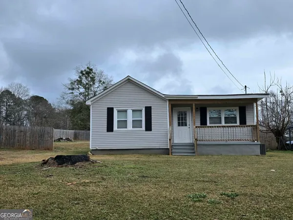 a front view of house with yard and trees in the background