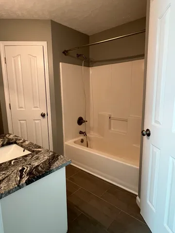 a bathroom with a granite countertop sink and a bathtub with shower