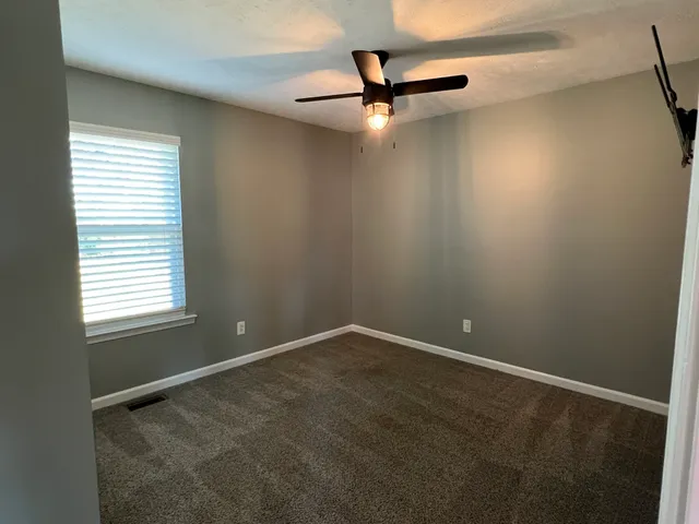 an empty room with a window and a fan