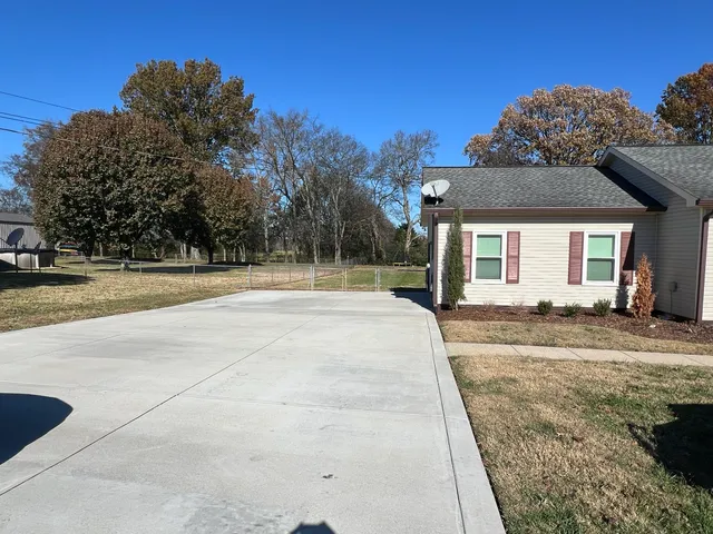 a view of a house with a yard and large tree