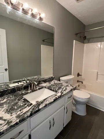 a bathroom with a granite countertop sink a toilet and a mirror