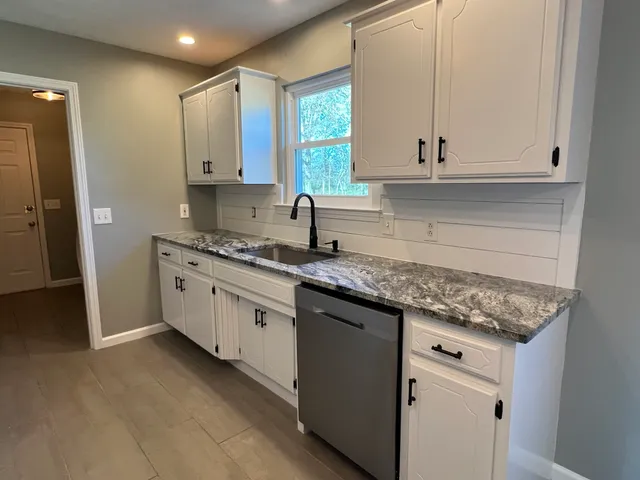 a kitchen with granite countertop white cabinets and white stainless steel appliances