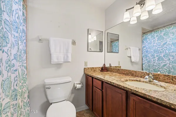 a bathroom with a granite countertop toilet sink and mirror